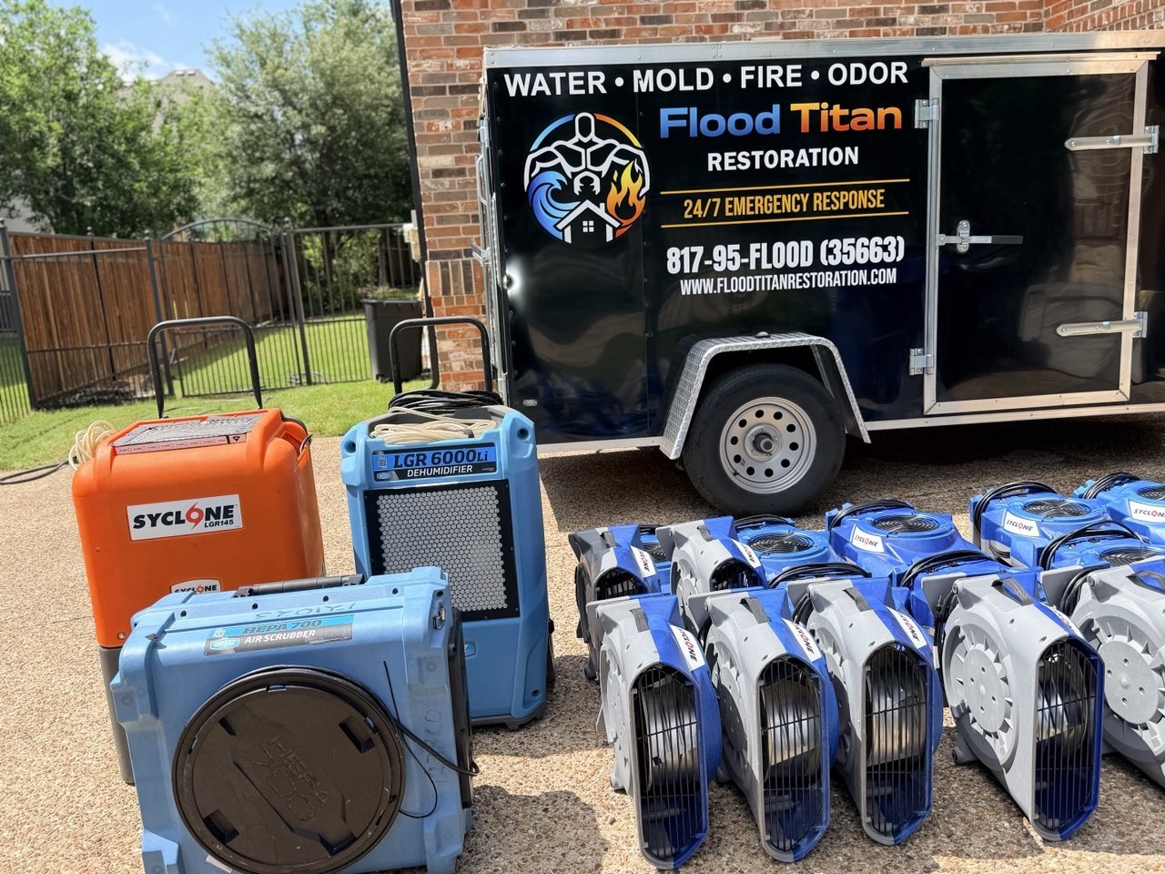 Flood Titan Restoration trailer staged at a Southlake driveway with an LGR dehumidifier, HEPA air scrubber, portable extractor, and a fleet of axial air movers lined up ready to deploy on a water-loss callout