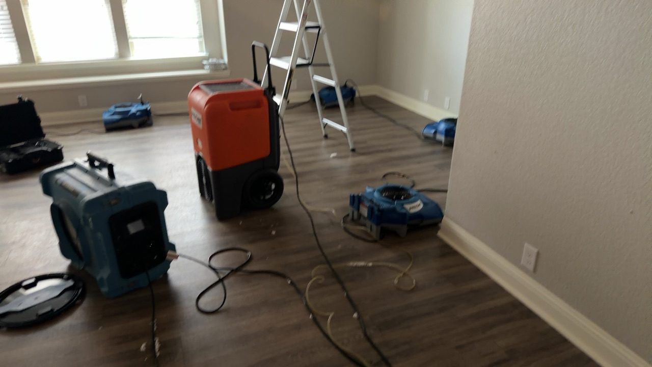 Air movers and a dehumidifier arranged in a living room during structural drying after a residential water damage loss.