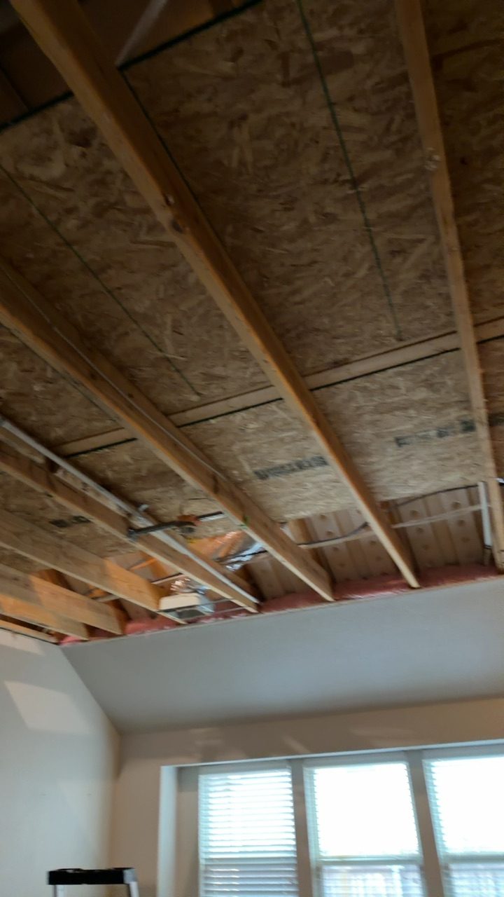 A bathroom wall cavity opened by a restoration crew showing wet drywall, swollen baseboard, and stained framing where a toilet supply line had been leaking.